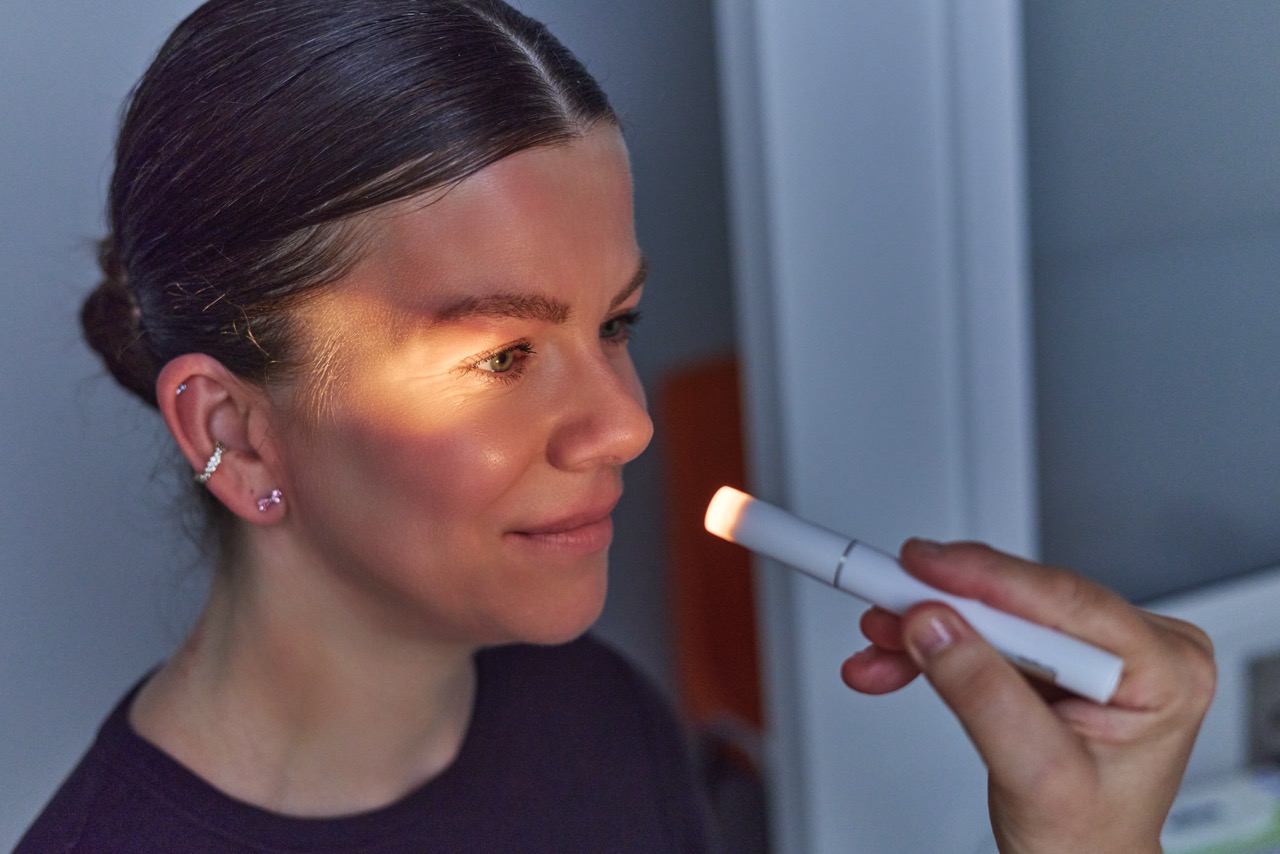 Frau wird mit Lichtquelle am Auge untersucht